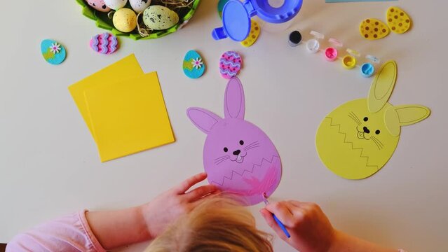 a little girl made an Easter egg out of paper and painted it with paints.