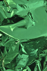 Crumpled green aluminum foil reflective texture background