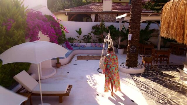 Aerial view of Woman is walking in bathrobe in poolbar and lying on pool sofa, sunlight, day time, summer time