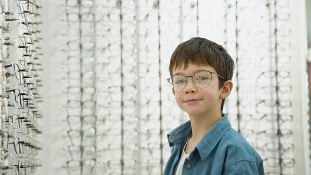 Portrait of a little boy in optics store in new glasses. Ophthalmology concept