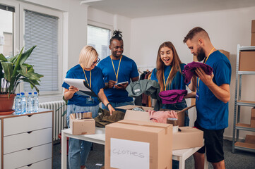 Diverse volunteers working in a charity donation center and packing clothes and food