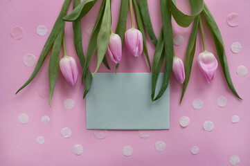 pink tulips with a grey copy space on a pink background with white confetti