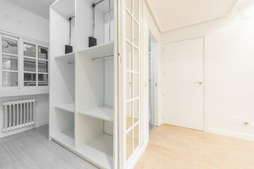 A bedroom dressing room with white and mirror aluminum sliding doors and many shelves