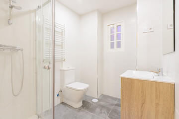 Fototapeta na wymiar bathroom with a wooden sink below a frameless wall-hung mirror, a walk-in shower with screens, a heated towel rail and white wooden doors