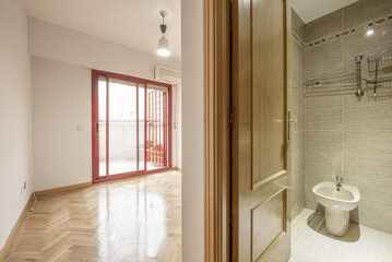 Fototapeta na wymiar Bedroom with en-suite bathroom and exit to a terrace with red aluminum sliding doors with bars