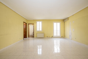 Empty room with aluminum radiator, sapele doors to access other rooms and white aluminum doors to a balcony with views