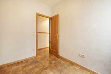 Empty room with gotelet white painted walls, oak wooden doors and matching skirting boards and oak parquet slatted floors laid in a checkerboard pattern