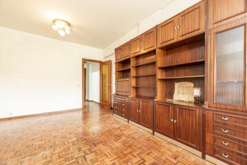 Obraz premium Living room of an empty house with old custom-made wooden bookcase in sapele veneer and parquet tile floors laid in checkered