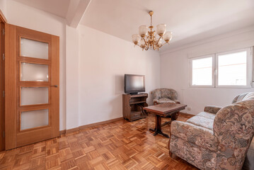 Living room with upholstered sofa with ugly pattern, wooden folding table in the center and sideboard with tv