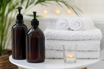 Obraz na płótnie Canvas Bathroom with towels, candles, bottles and tropical plant