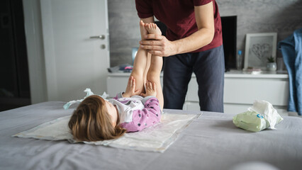 man caucasian father change diapers to his daughter toddler in bedroom - obrazy, fototapety, plakaty