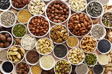 Colorful mix of various nuts and seeds: peanut and cashew, hazelnut and almond, pine nuts and walnut; healthy diet snack; vegan food background	