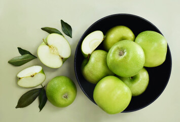Bowl of fresh ripe harvested green apples from market with leaves, selective focus, shallow DOF