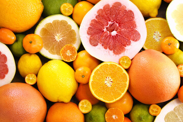 Colorful bright background of fresh ripe sweet citrus fruits: orange and tangerine, green lime and yellow lemon, grapefruit and kumquat
