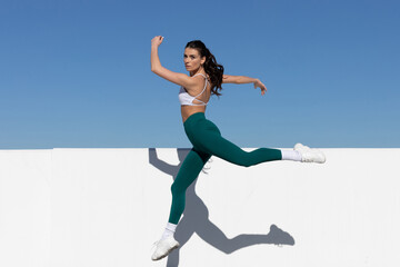 woman in exercise clothes jumping in the air, space for text
