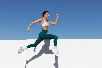 athletic woman running or jumping in the air, focus on face, space for text