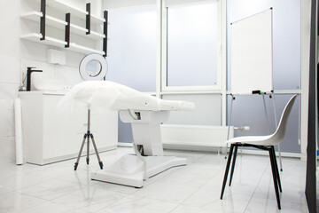 Fototapeta na wymiar empty white beautician office. medical room with modern cosmetology equipment and a couch in the clinic