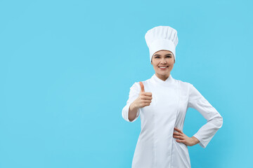 Happy female chef showing thumbs up on light blue background. Space for text