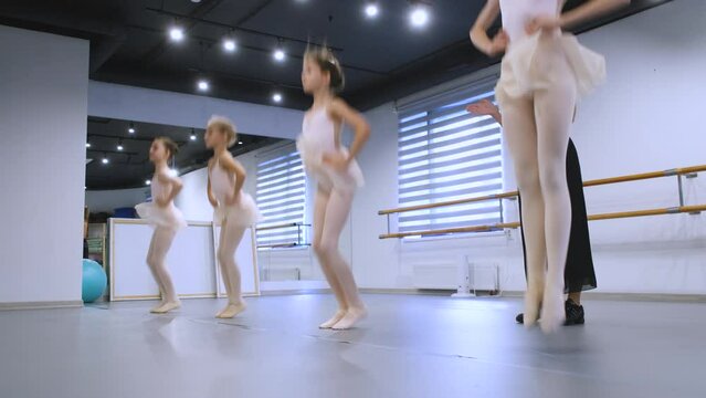at a ballet lesson, four girls jump and warm up