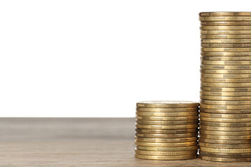Many golden coins stacked on wooden table against white background, space for text