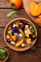 Delicious persimmon salad with cheese and pomegranate served on wooden table, flat lay