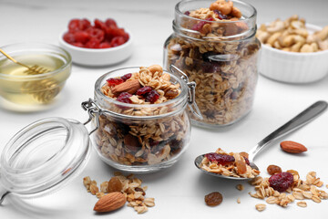Jars of tasty granola with nuts and dry fruits on white marble table