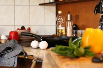 Fresh eggs and bell pepper on wooden countertop in kitchen. Ingredients for breakfast