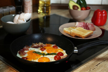Tasty eggs with tomatoes and bacon in frying pan for breakfast