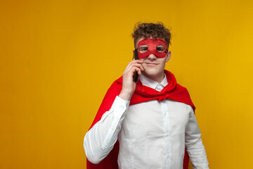 guy in a superhero costume talking on the phone on a yellow background, super man communicates with...