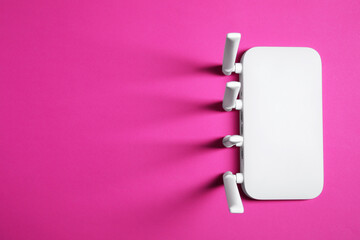 New white Wi-Fi router on pink background, top view. Space for text