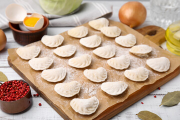Fototapeta na wymiar Raw dumplings (varenyky) with tasty filling and ingredients on white wooden table