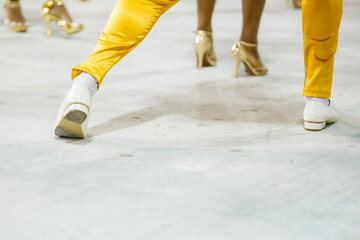 legs of a sambista dancing, with yellow pants and white shoes at the sambodromo da marques de...
