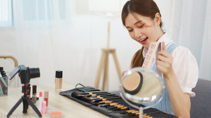 Beauty blogger concept, Asian woman use brush to applying eye shadow and review in live streaming