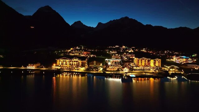 Aerial View Over Illuminated Pertisau Village At Night On The Achensee Lake In The Tyrol Region Of Austria - drone shot
