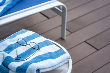 Pool towel on table and lounge chair. Summer vacation concept.