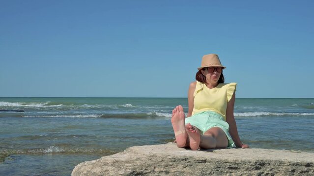 Young woman sitting on a stone and watching the the horizon. 4k video footage UHD 3840x2160