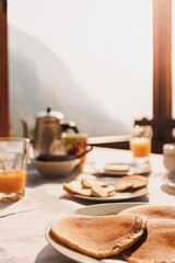 European breakfast set with pancakes juice and honey with sunlight from windows.