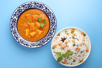 Paneer Butter Masala Curry, Paneer or Cottage Cheese. This is a rich creamy curry made with paneer, spices, onions, tomatoes, cashews and butter served with vegetable pulao - obrazy, fototapety, plakaty