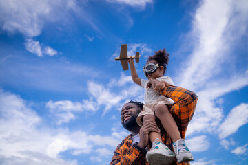 Happy African American father engineer carrying his daughter with a blue sky background. Cheerful...