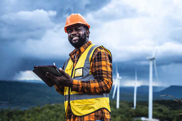 Portrait of engineer African American man working with laptop in wind turbine farm.