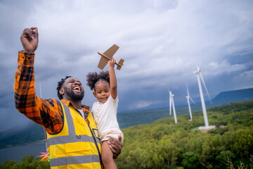 Happy African American father engineer carrying his daughter playing at the Wind turbine.