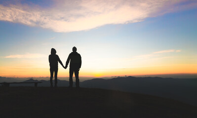 Fototapeta na wymiar Silhouette of a couple on the mountain, A young romantic couple enjoy a beautiful view of the sun setting over the mountains, love, Valentine's Day.