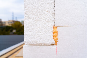 The corner of the house is insulated with polystyrene foam insulation close-up. Preparing a private...