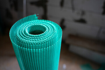 New roll of green plaster mesh close-up. Building materials for wall plastering close-up on a blurred background
