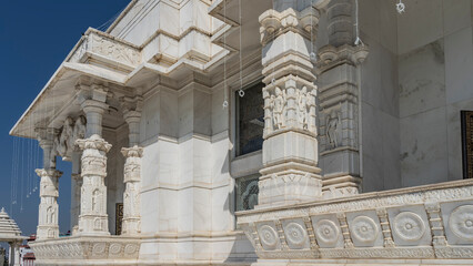 A fragment of the ancient white marble temple Birla Mandir (Lakshmi Narayana) against the blue sky. Carved columns and decorative ornaments are visible. India. Jaipur
