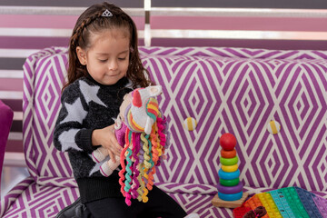 A girl plays with a doll sitting on the couch of a pediatric doctor's office, with room to copy.