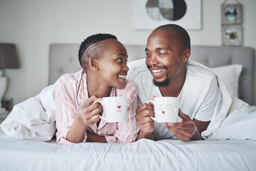 Coffee, bed and morning with a black couple together in the bedroom of their home to relax on the weekend. Love, tea or early with young man and woman relaxing while bonding in their house