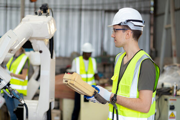 Young caucasian engineer man using remote control with ai robot machine arm automatic for manufacture production at the factory, robotic electronic and intelligence technology, industry concept.
