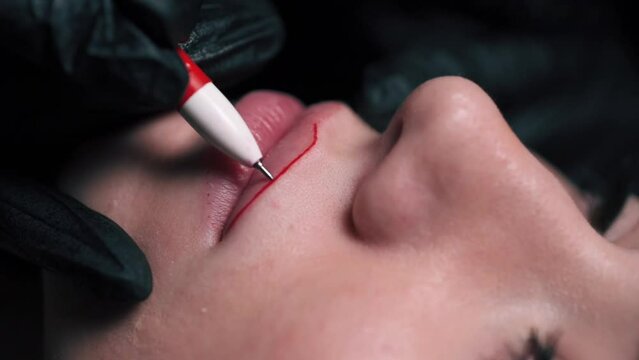 Permanent lip makeup. Beautician makes lip contour marks. Extreme close-up.