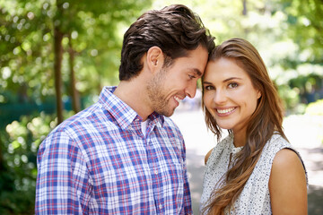 Fototapeta premium Portrait, couple and hug in park with forehead, touch and bonding against a blurred background. Face, embrace and man with woman in nature, smile and excited for reunion, relationship or togetherness